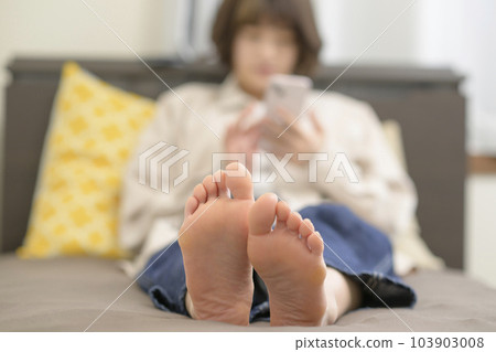 Young woman looking at smartphone in bed 103903008