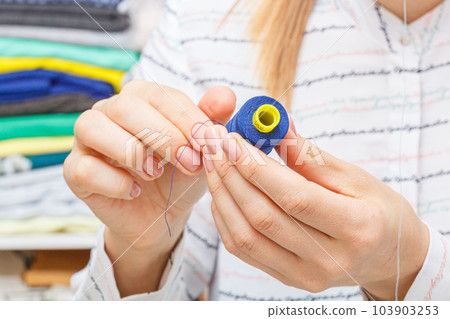 Adjusting the sewing machine, threads in female hands Adjusting the sewing machine, threads in female hands 103903253