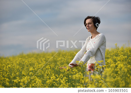 Beautiful Caucasian girl listening to music with headphone in the outdoors 103903501