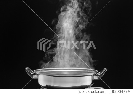 Steam over cooking pot in kitchen on dark background. Steam over cooking pot in kitchen on dark background. 103904759