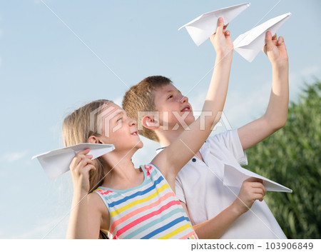 Two kids with paper planes outdoors. Two kids with paper planes outdoors. 103906849