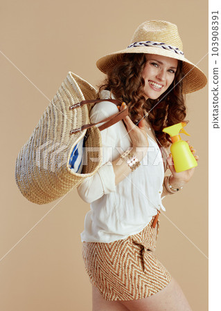 happy 40 years old housewife in blouse and shorts against beige 103908391