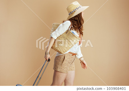 Seen from behind woman in blouse and shorts on beige Seen from behind woman in blouse and shorts on beige 103908401