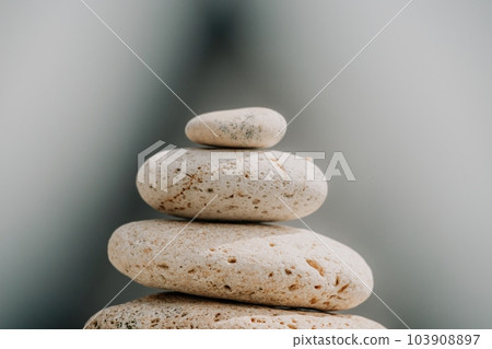 Balanced rock pyramid on sea pebbles beach, sunny day and clear sky at sunset. Golden sea bokeh on background. Selective focus, zen stones on sea beach, meditation, spa, harmony, calm, balance concept 103908897