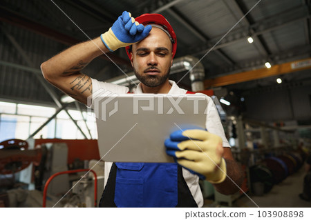 African american male manager in electric cable warehouse holding digital tablet 103908898