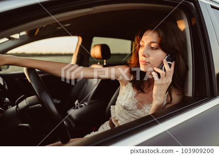 Portrait of woman talking on mobile phone while driving her car Portrait of woman talking on mobile phone while driving her car 103909200