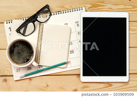 Top view of wooden table with white digital tablet with black screen on it Top view of wooden table with white digital tablet with black screen on it 103909509
