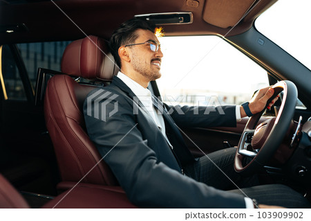 Young businessman in elegant suit driving luxury car Young businessman in elegant suit driving luxury car 103909902