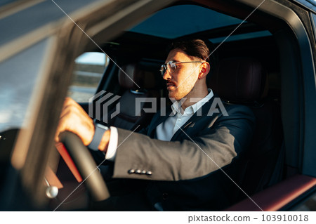 Young businessman in elegant suit driving luxury car Young businessman in elegant suit driving luxury car 103910018