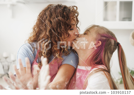 Mother and daughter having fun while cooking dough in kitchen Mother and daughter having fun while cooking dough in kitchen 103910137