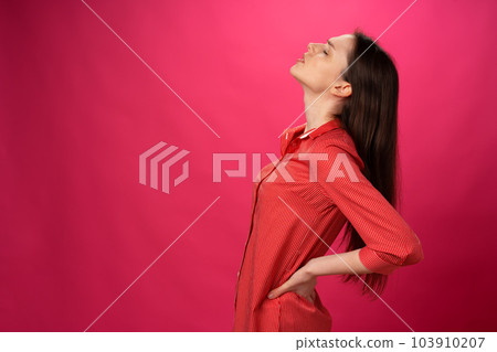 Brunette girl got back pain against pink background Brunette girl got back pain against pink background 103910207