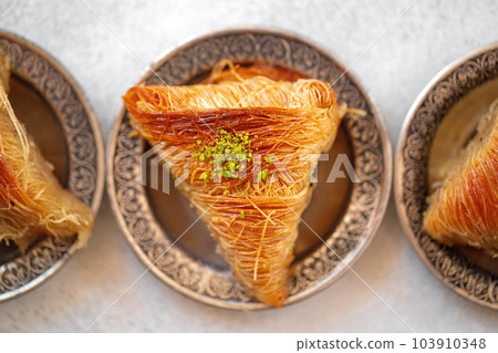 Turkish baklava on oriental metal plate on white table Turkish baklava on oriental metal plate on white table 103910348