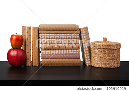 Stack of books and apple on tabletop against white background 103910919