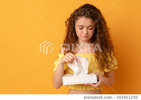Sick young woman holding tissue handkerchief against yellow background Sick young woman holding tissue handkerchief against yellow background 103911250