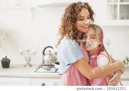 Mother and daughter having fun while cooking dough in kitchen 103911251