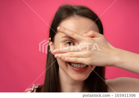 Young woman smiling and covering her face with hand, studio portrait Young woman smiling and covering her face with hand, studio portrait 103911306