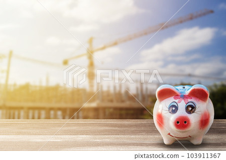 Piggy Bank on wood desk and blur construction background. Piggy Bank on wood desk and blur construction background. 103911367