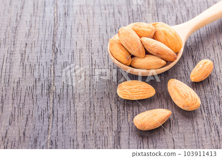 Peeled almonds in wooden spoon on wood background. 103911413