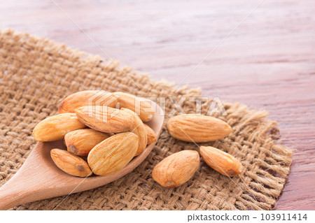 Peeled almonds in wooden spoon on wood background. 103911414