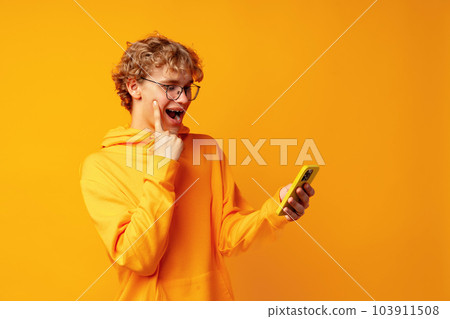 Happy caucasian young man using smartphone against yellow background Happy caucasian young man using smartphone against yellow background 103911508