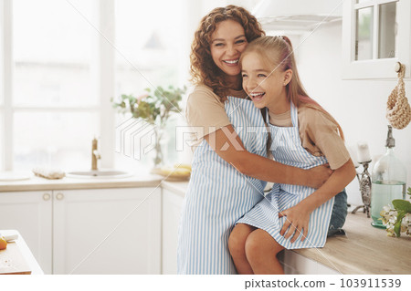 Portrait of a teen girl with her mother at home in kitchen 103911539
