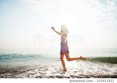 Portrait of young woman walking on the beach on sunrise 103911912
