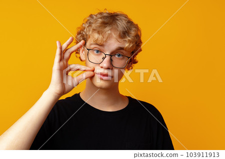 Young man telling to be quiet on yellow background in studio Young man telling to be quiet on yellow background in studio 103911913