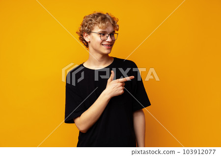 Handsome young man pointing finger to copy space on yellow banner background 103912077