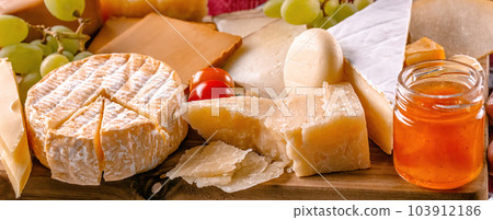 Parmesan and different kinds of cheese served with grapeand honey closeup. Organic brie and camambert set delicatessen collection Parmesan and different kinds of cheese served with grapeand honey closeup. Organic brie and camambert set delicatessen collection 103912186