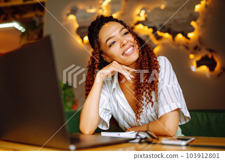 Portrait of African American woman sitting at cafe having video call on laptop computer. 103912801