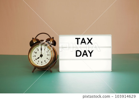 Tax Day text message on paper card with wooden easel and alarm clock Tax Day text message on paper card with wooden easel and alarm clock 103914629