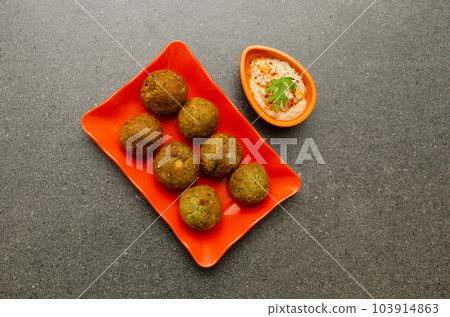 Traditional Egyptian dish Falafel with hummus served in Orange colored plate on Gray background Traditional Egyptian dish Falafel with hummus served in Orange colored plate on Gray background 103914863