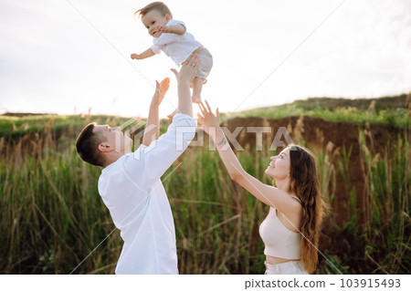 Cheerful young family with little baby boy spending time together on the beach. 103915493