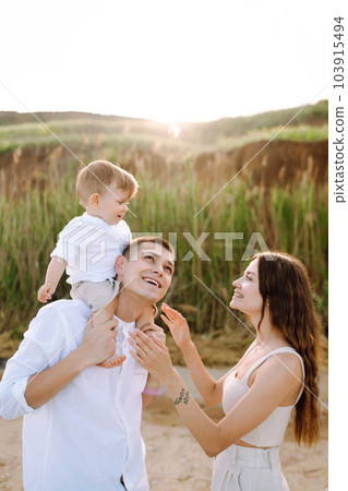 Cheerful young family with little baby boy spending time together on the beach. Cheerful young family with little baby boy spending time together on the beach. 103915494