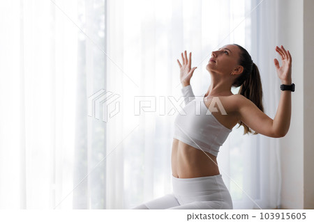 Young woman in white top stretching her body during fitness training 103915605