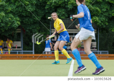 Young woman on the pitch playing field hockey game Young woman on the pitch playing field hockey game 103915626