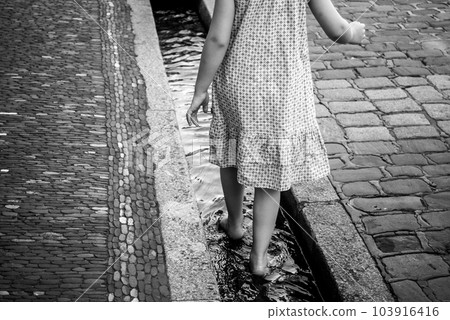 Portrait on back view of young woman walking in the water in the city 103916416