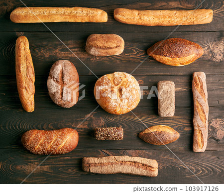 Different types of bread loaves on dark wooden background 103917126