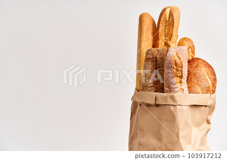 Different types of french bread baguettes in paper bag over white background with copy space 103917212