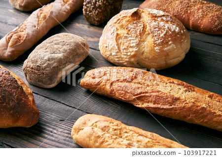 Different types of bread loaves on dark wooden background 103917221