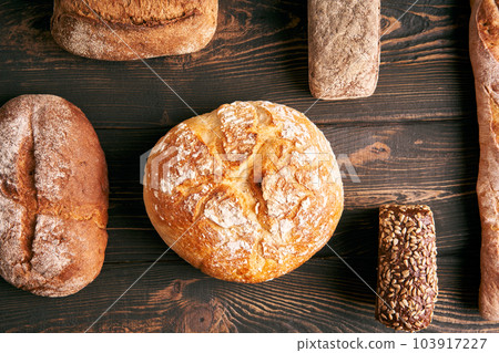 Different types of bread loaves on dark wooden background Different types of bread loaves on dark wooden background 103917227