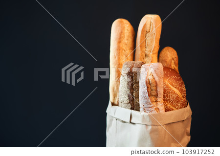 Different types of french bread baguettes in paper bag over dark background with copy space 103917252