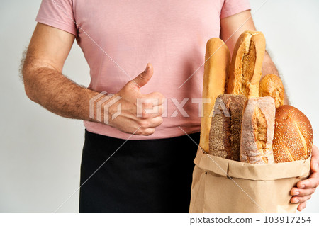 Man holds fresh loaves of bread baguettes in paper bag over light background Man holds fresh loaves of bread baguettes in paper bag over light background 103917254