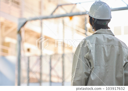 一個穿著工作服的男人抬頭看著建築工地的背影 103917632