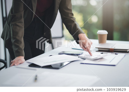 Concept of business office woman working,Businesswoman smile while working about her invesment plan with analyzing document and business investment graph data by using laptop on desk in workstation. 103919629