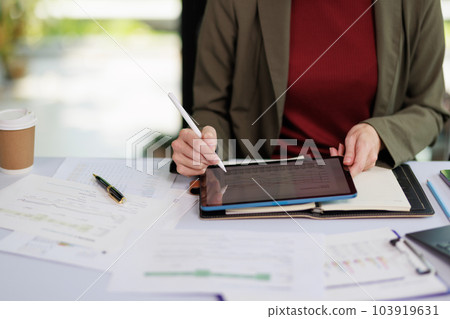 Concept of business office woman working,Businesswoman smile while working about her invesment plan with analyzing document and business investment graph data by using laptop on desk in workstation. Concept of business office woman working,Businesswoman smile while working about her invesment plan with analyzing document and business investment graph data by using laptop on desk in workstation. 103919631