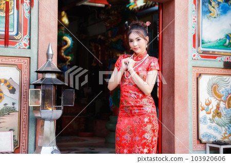 Chinese woman in a red cheongsam dress pay homage to Chinese god at shrine. Concept to celebrate Chinese New Year. Chinese woman in a red cheongsam dress pay homage to Chinese god at shrine. Concept to celebrate Chinese New Year. 103920606