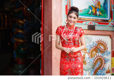 Chinese woman in a red cheongsam dress pay homage to Chinese god at shrine. Concept to celebrate Chinese New Year. Chinese woman in a red cheongsam dress pay homage to Chinese god at shrine. Concept to celebrate Chinese New Year. 103920611