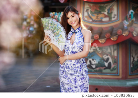 Chinese woman in cheongsam dress holding fan at shrine. Concept to celebrate Chinese New Year. 103920653