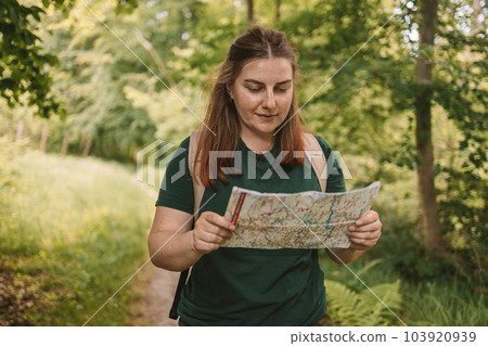 Young woman hiker reading map hiking trip looking to find place to go,, having fun and relaxing while spending summer day outdoors, female traveler choosing best route for destination using map during Young woman hiker reading map hiking trip looking to find place to go,, having fun and relaxing while spending summer day outdoors, female traveler choosing best route for destination using map during 103920939